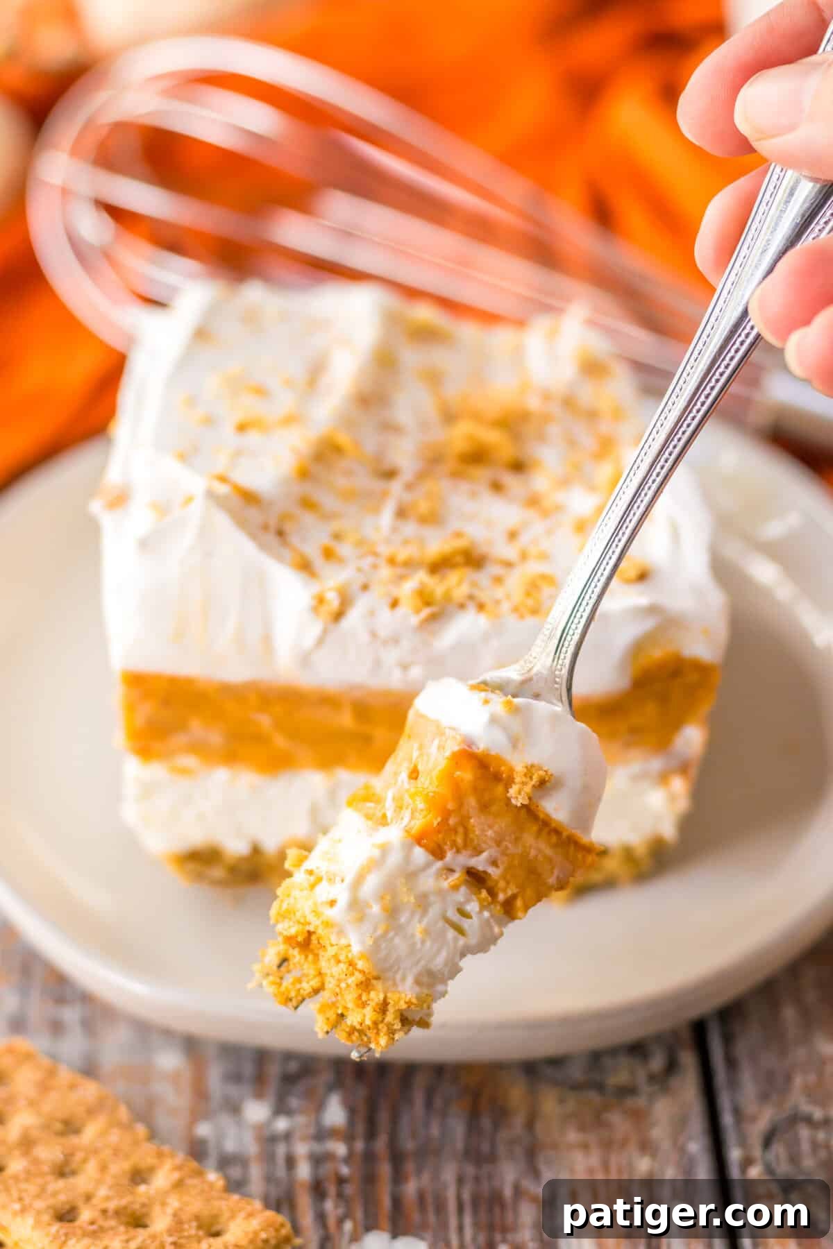 A forkful of pumpkin delight showing four distinct layers, highlighting the dessert's creamy texture and appealing structure.