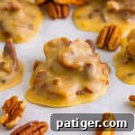 Southern pecan pralines on parchment paper with pecans around them.