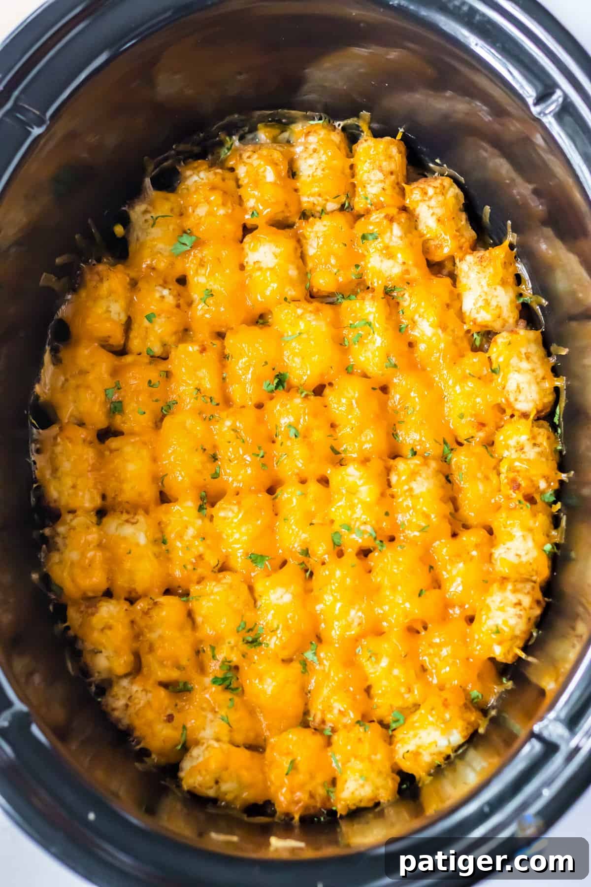 Slow cooker tater tot casserole topped with melted cheese.