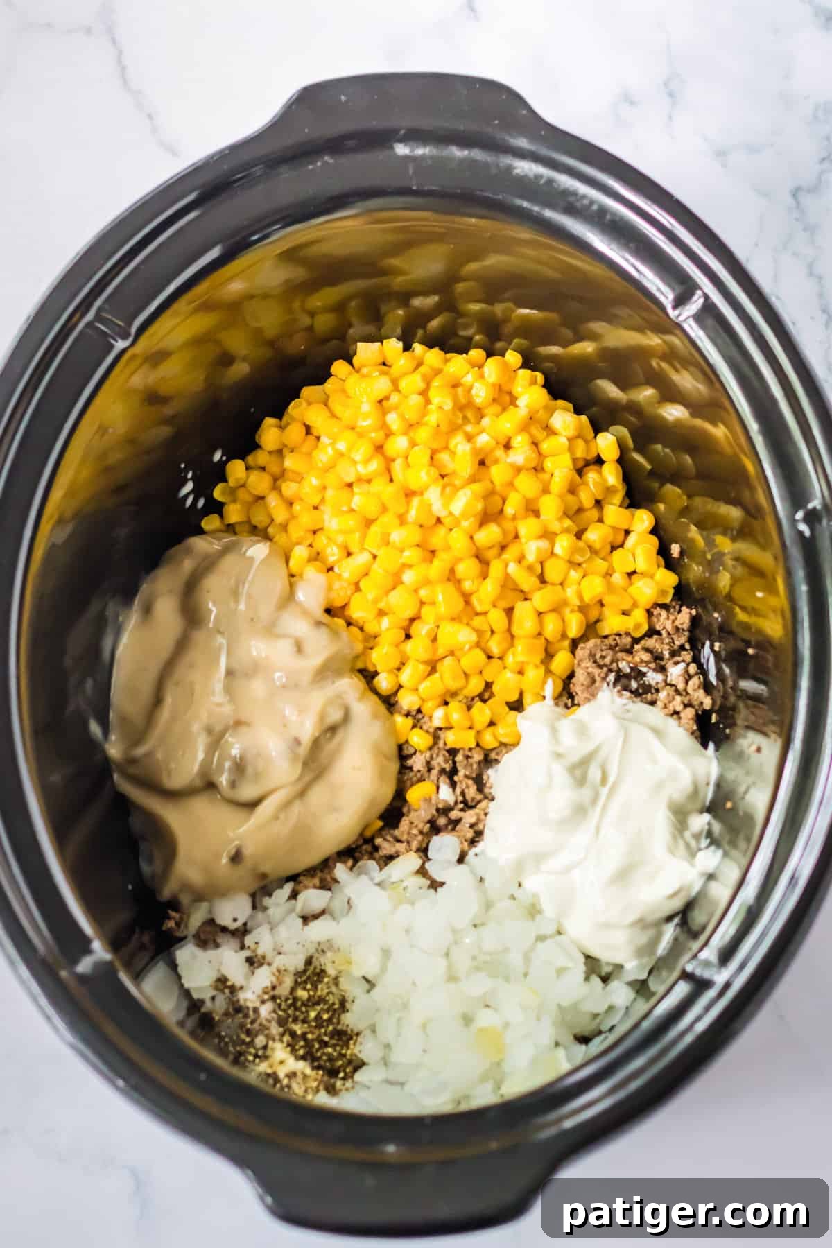 Ground beef, corn, soup, onion, seasonings, milk, and sour cream added to crockpot.