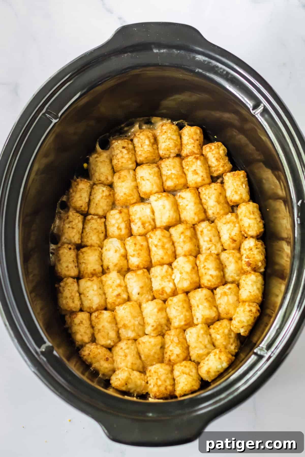 Tater tots in a neat and even layer in crock pot.