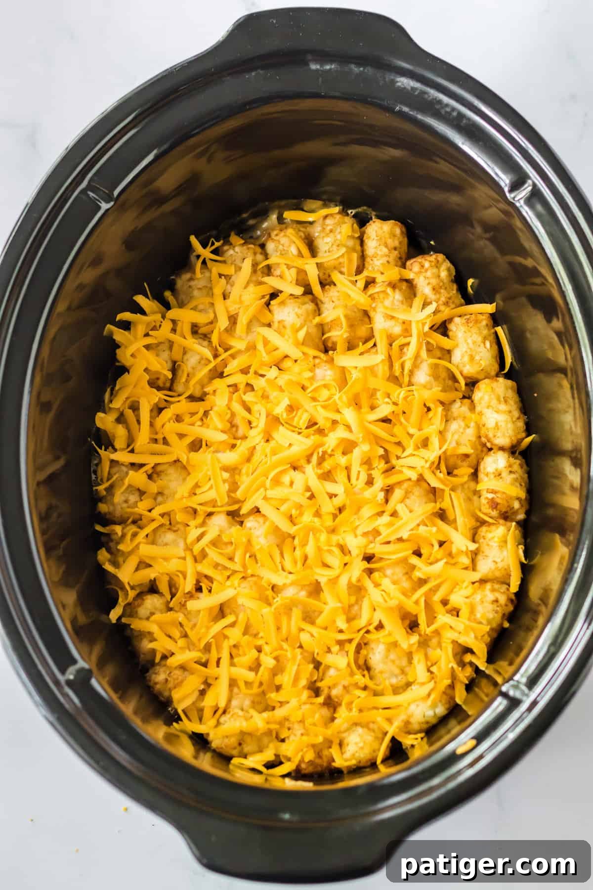 Shredded cheese on top of tater tot casserole in crockpot.
