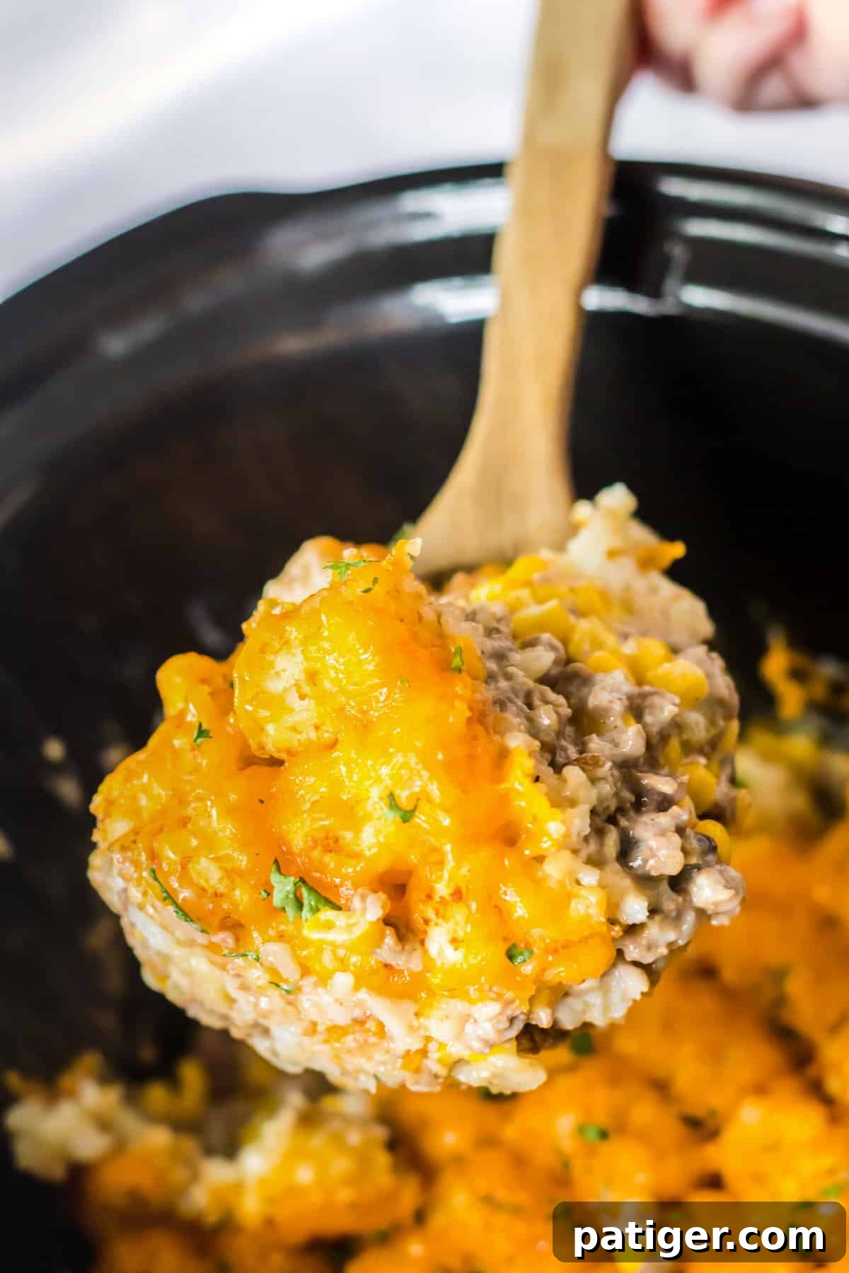 Spoon scooping out serving of slow cooker tater tot casserole.
