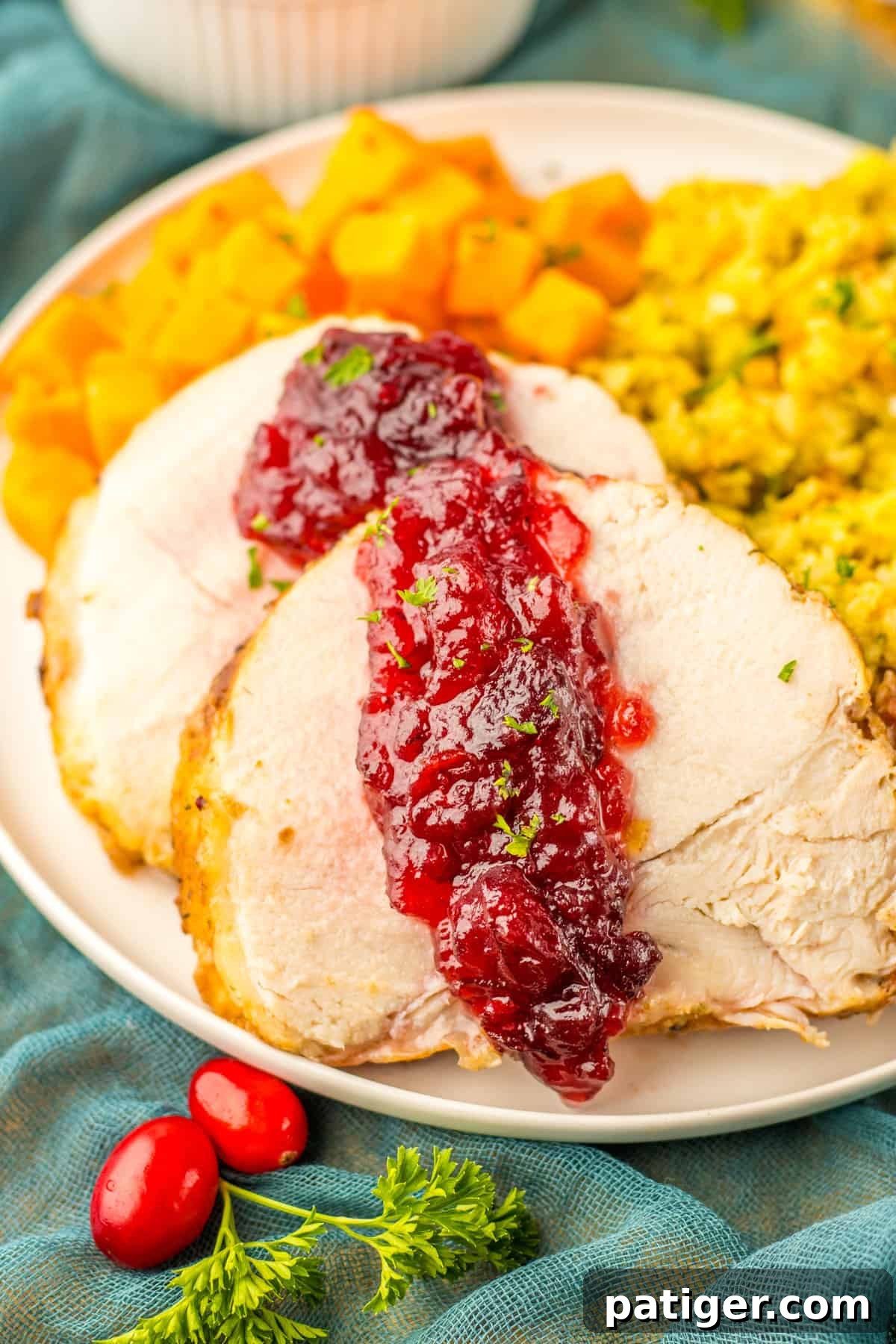Tender Slow Cooker Boneless Turkey Breast 2 Slow cooked boneless turkey breast topped with cranberry sauce and served with stuffing and sweet potatoes, making an inviting holiday spread.