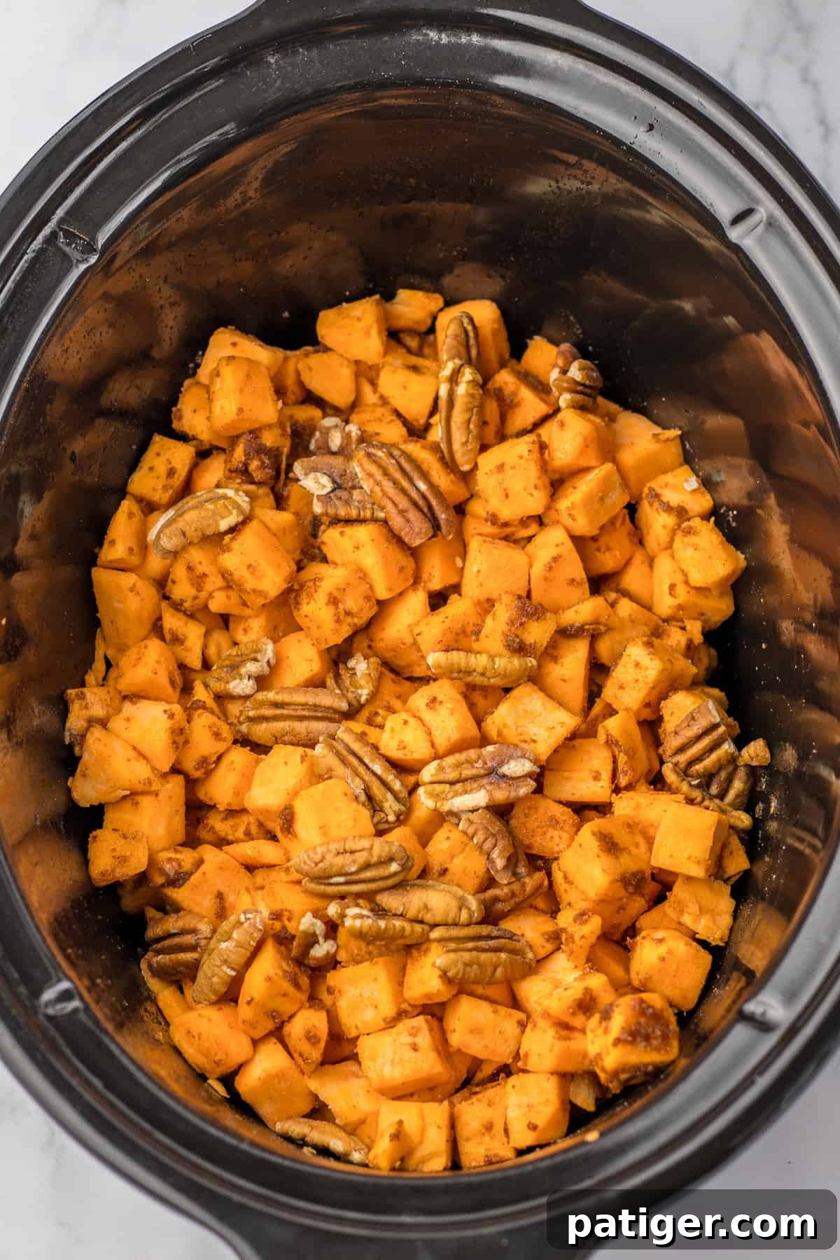 Slow Cooker Sweet Potato Bliss 6 Diced sweet potatoes and pecans in a slow cooker, before cooking.