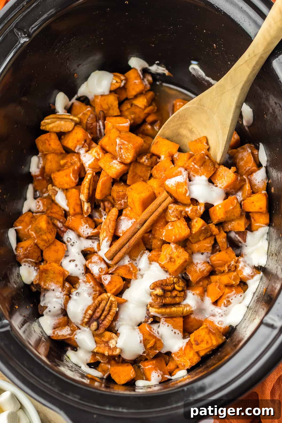 Slow Cooker Sweet Potato Bliss 7 Crockpot sweet potato casserole with a wooden spoon in it and leaning on the side of the insert, showing the finished dish.