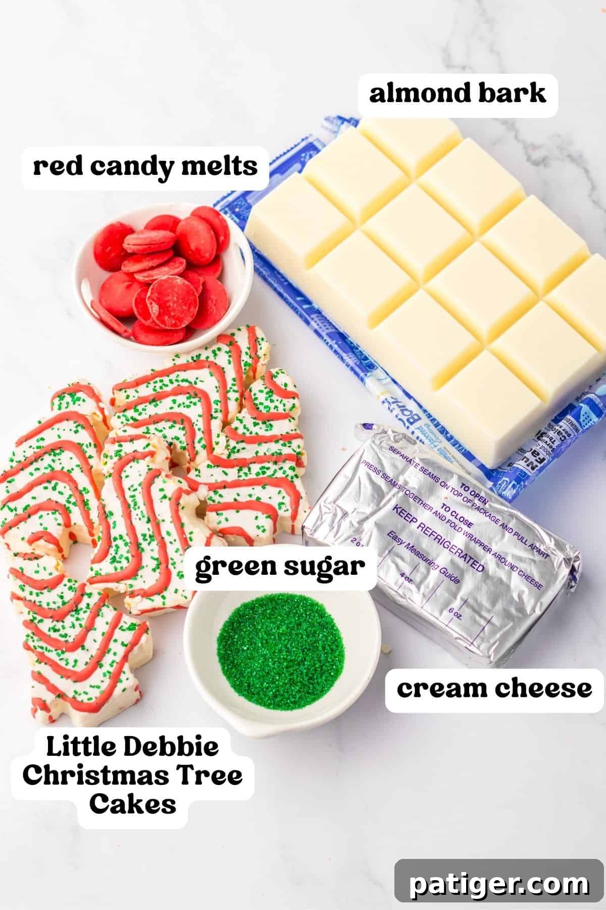 A flat lay of ingredients for Christmas cake truffles: red candy melts, white almond bark, vibrant green sanding sugar, softened cream cheese, and a stack of Little Debbie Christmas Tree Cakes.