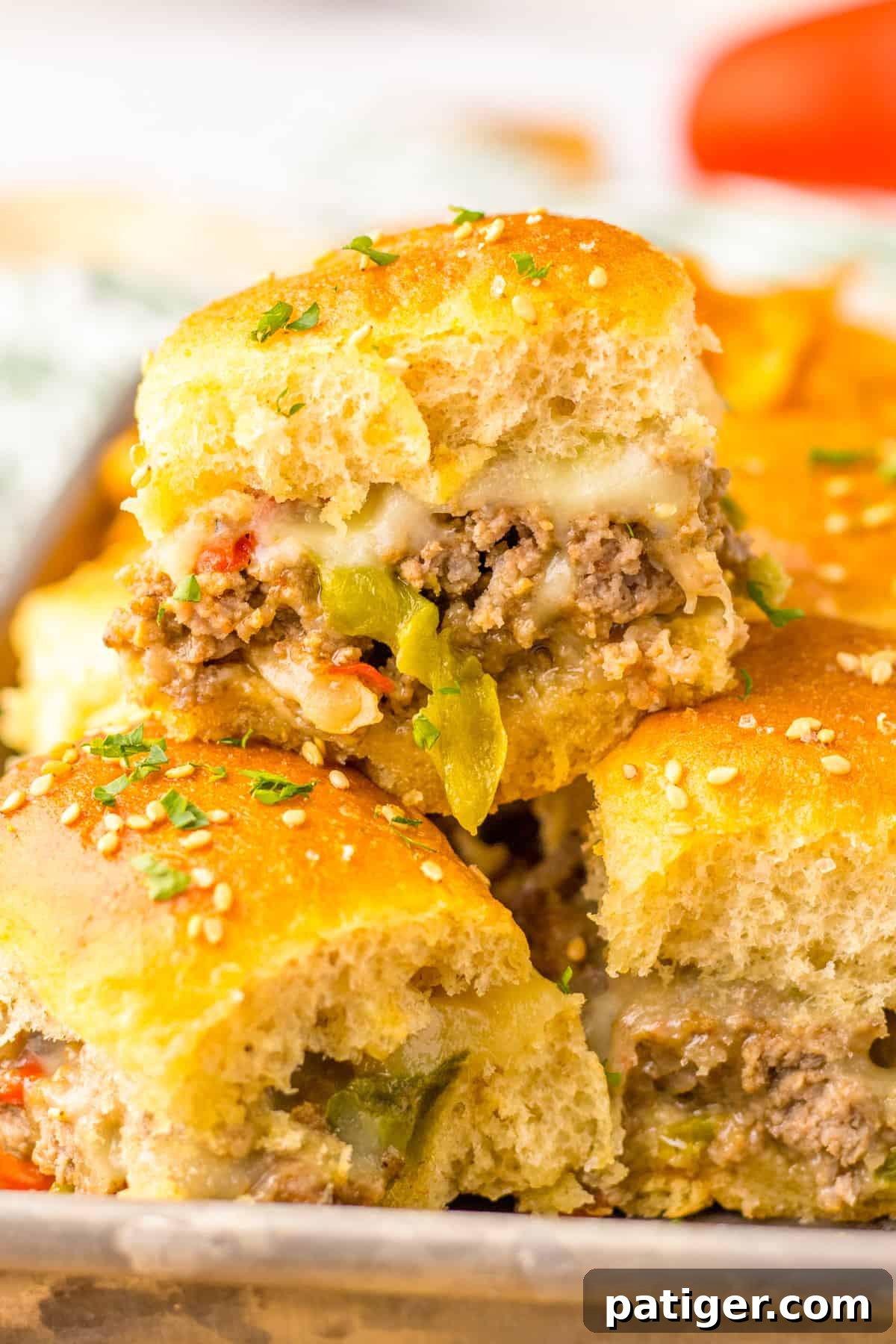 Gooey Philly Slider Perfection 2 Philly Cheesesteak Sliders with Ground Beef, peppers, onions, and provolone cheese on Hawaiian Rolls, garnished with parsley.