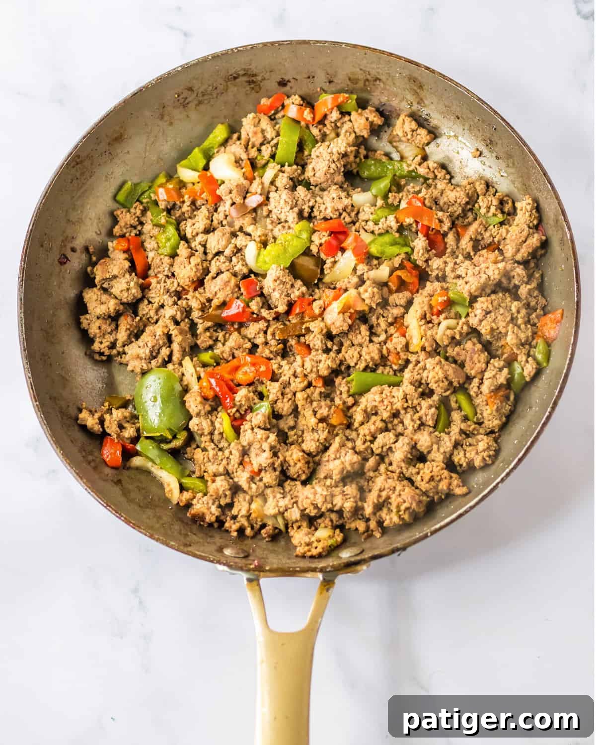 Gooey Philly Slider Perfection 5 Browned lean ground beef, colorful bell peppers, and diced onions cooking in a large frying pan.
