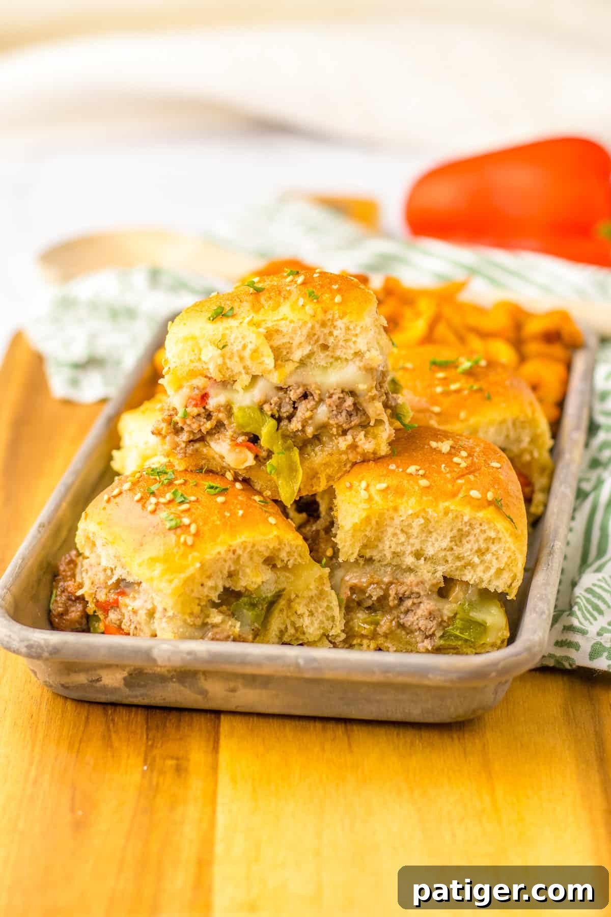 Gooey Philly Slider Perfection 10 Plate of ground beef Philly Cheesesteak Sliders with peppers, onions, and provolone cheese on Hawaiian Rolls, served alongside seasoned French fries.