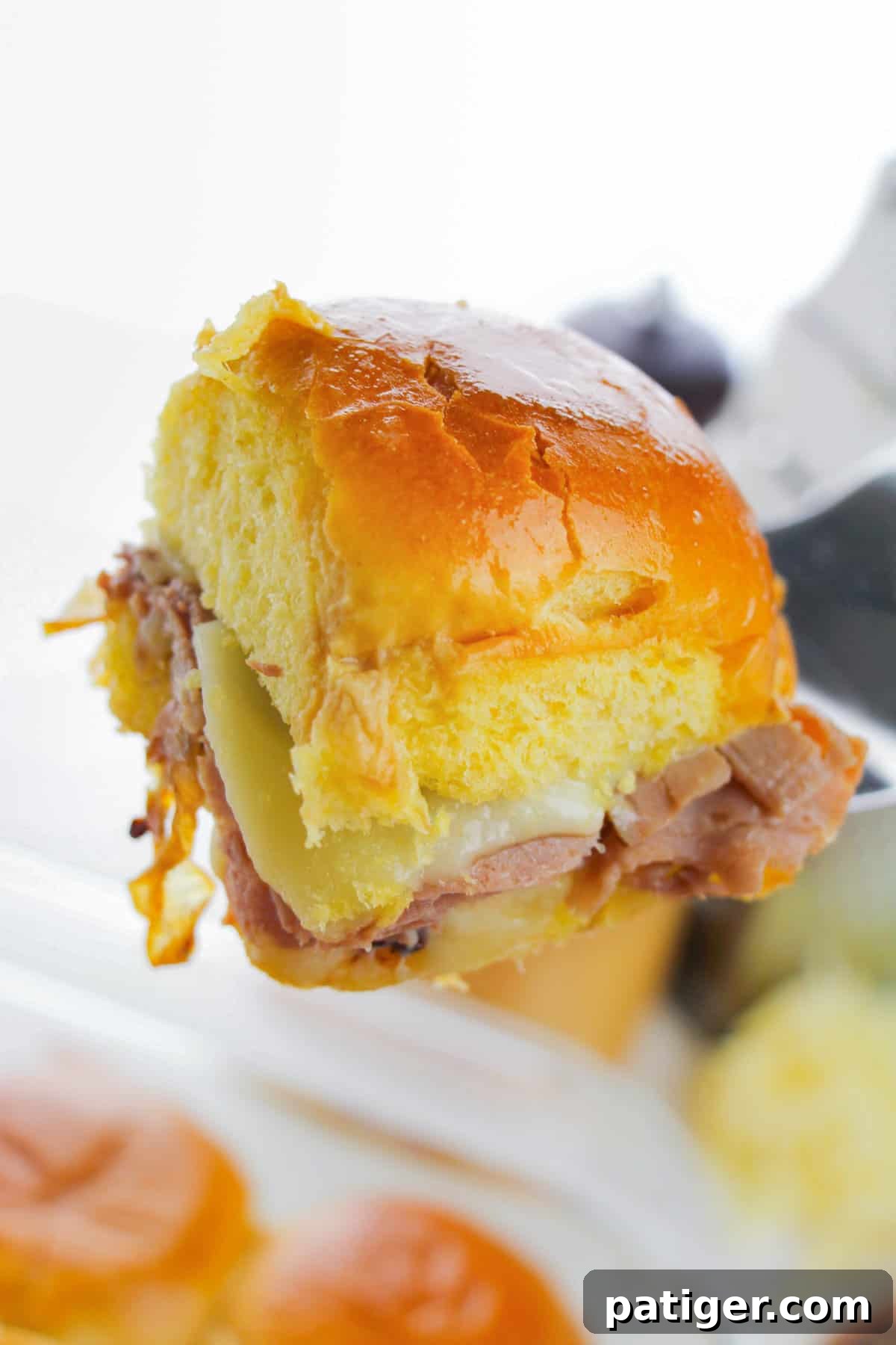 Metal spatula removing Hawaiian Roll French Dip Roast Beef Slider from pan.