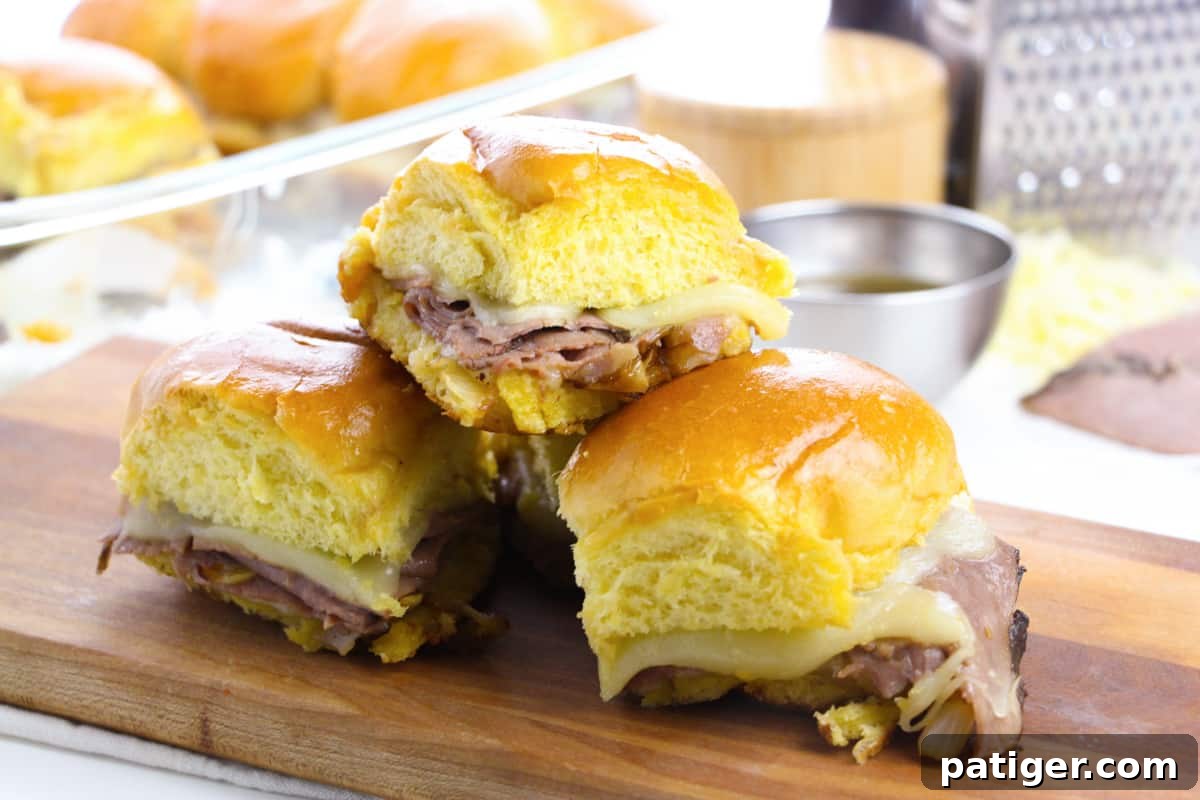 French Dip Roast Beef Sliders served on a wooden cutting board.