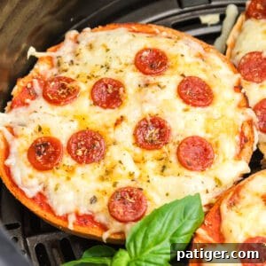 Air fryer pizza bagels with mini pepperonis in an air fryer basket.