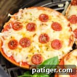 Air fryer pizza bagels with mini pepperonis in an air fryer basket.
