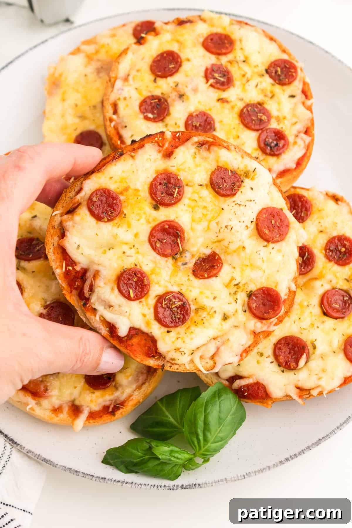Hand holding a homemade pepperoni pizza bagel.