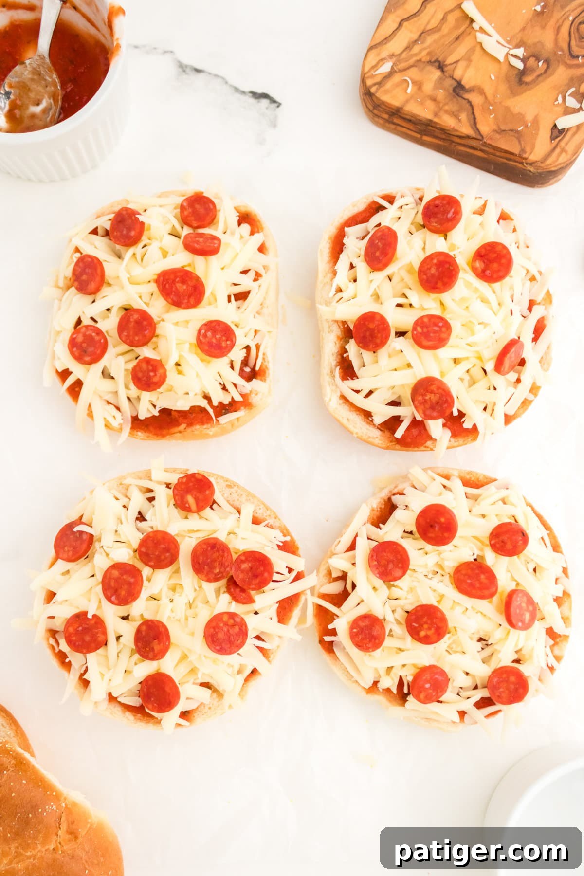 Uncooked bagel pizzas with shredded cheese and mini pepperonis.