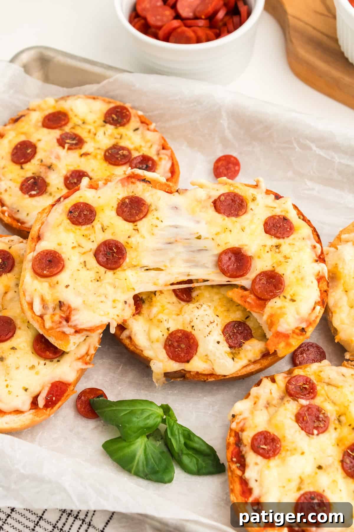 Pizza bagel torn in half to show melty cheese pull.