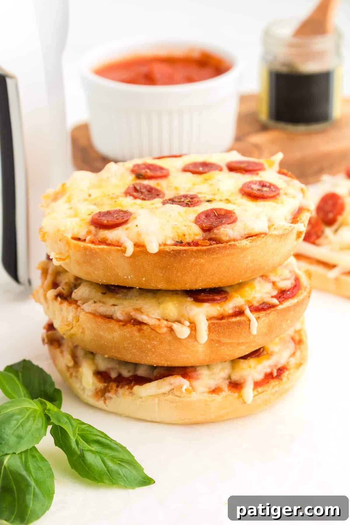 Three homemade pizza bagels with pepperoni stacked on top of one another.