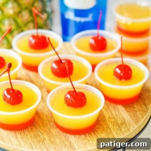 Caramel Pineapple Jell-O Shots 8 Pineapple upside down cake jello shots with two distinct layers: a red cherry bottom layer and yellow pineapple top layer, and a cherry on top.