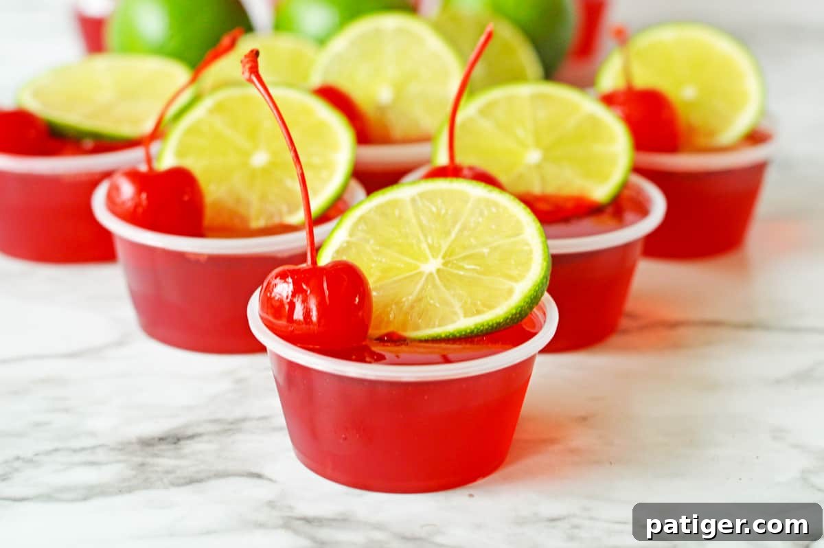 Cherry limeade jello shots made with vodka and topped with lime and cherry.