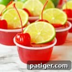 Cherry limeade jello shots made with vodka and topped with lime and cherry.