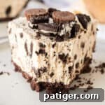 Decadent Oreo Peanut Butter Pie 12 Slice of Oreo Peanut Butter Pie with chocolate cookie crust, peanut butter filling with crushed Oreos, and Reese's and Oreos on top. A fork has taken a bite out of the pie.