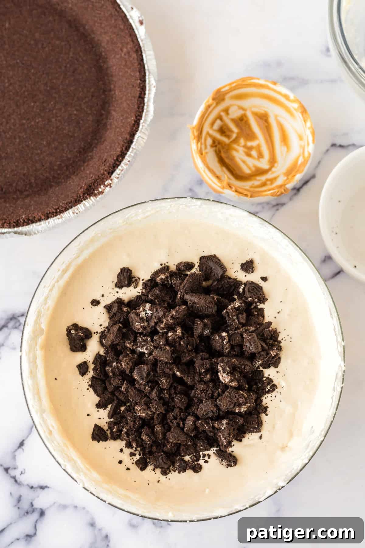 Decadent Oreo Peanut Butter Pie 6 Crushed Oreo cookie pieces being gently added and folded into the creamy peanut butter pie filling mixture.
