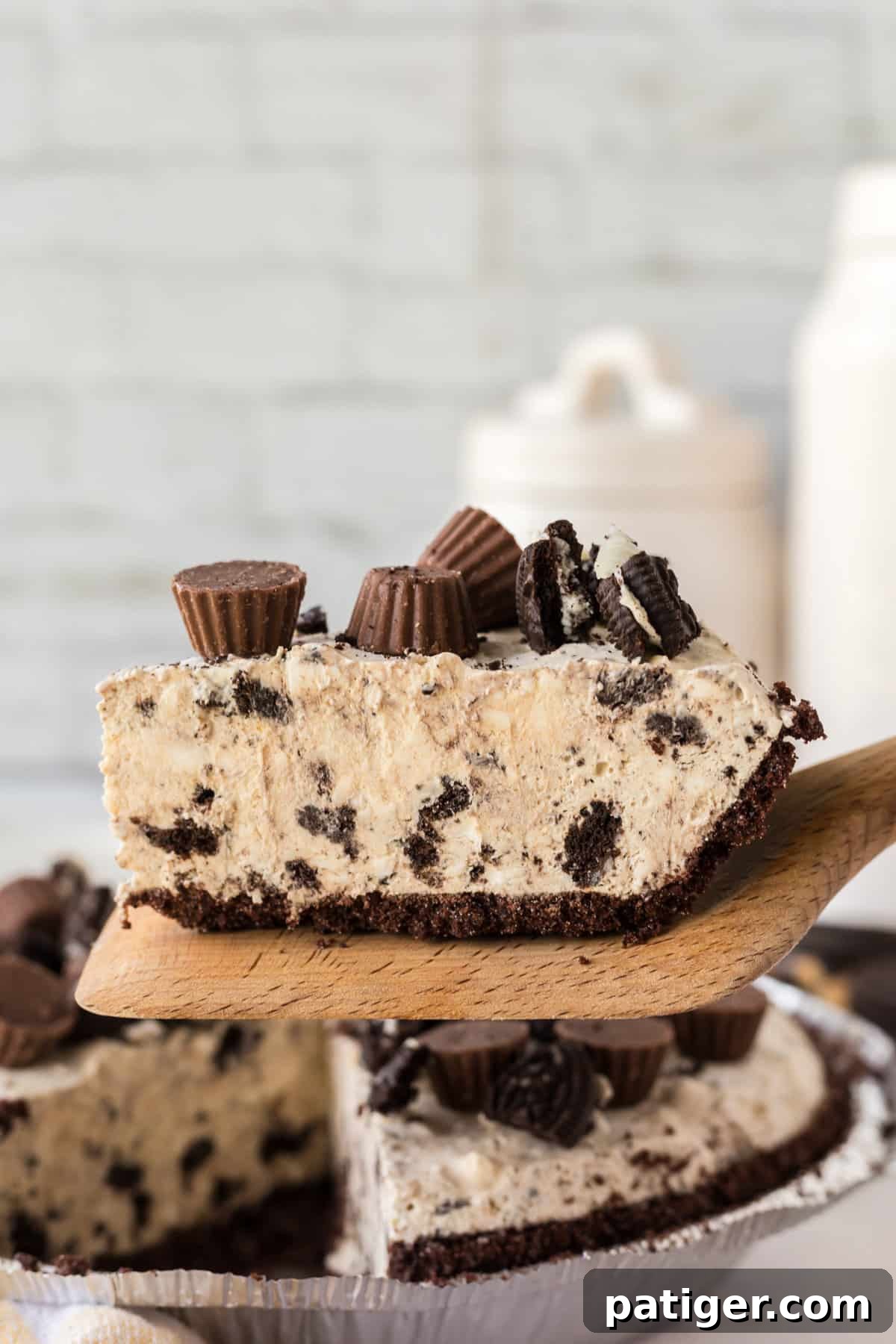 Decadent Oreo Peanut Butter Pie 9 A slice of no bake peanut butter pie with Oreo crust being lifted from the pie with a wooden server, ready to be enjoyed.