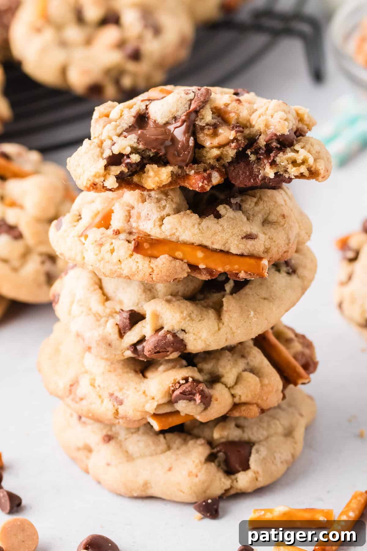 Mega Mix Cookies 10 Everything but the kitchen sink cookies stacked on top of one another with a bite taken out of the top cookie to show melted chocolate chips.