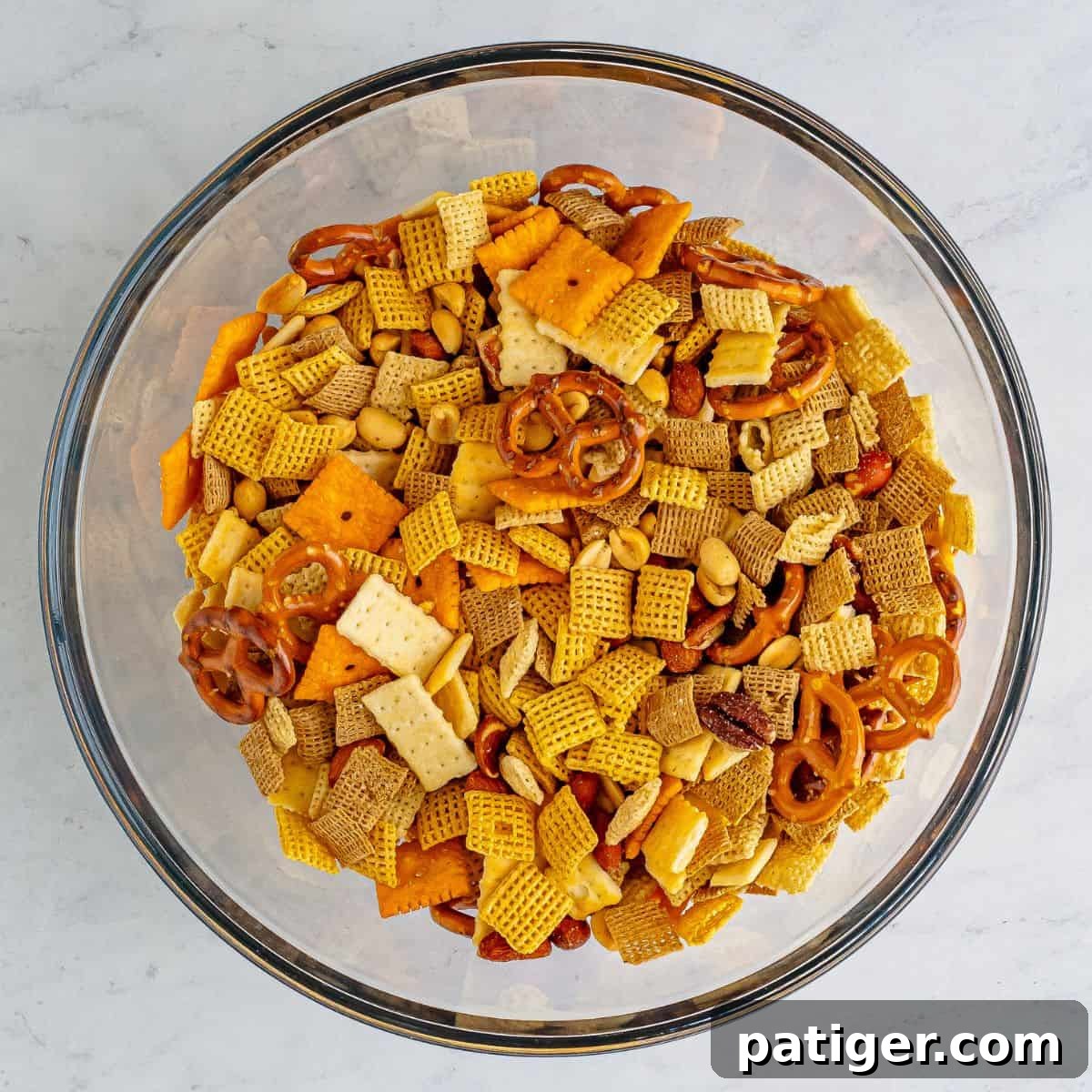 Blazin' Snack Fusion 4 Chex cereal, mini pretzels, cheeze-its, mini club crackers, and mixed nuts in a mixing bowl.