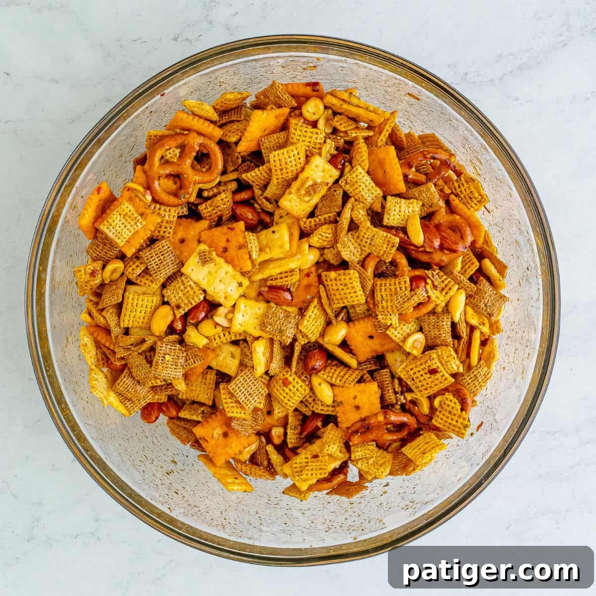 Blazin' Snack Fusion 6 Chex mix coated with sauce in a glass mixing bowl.