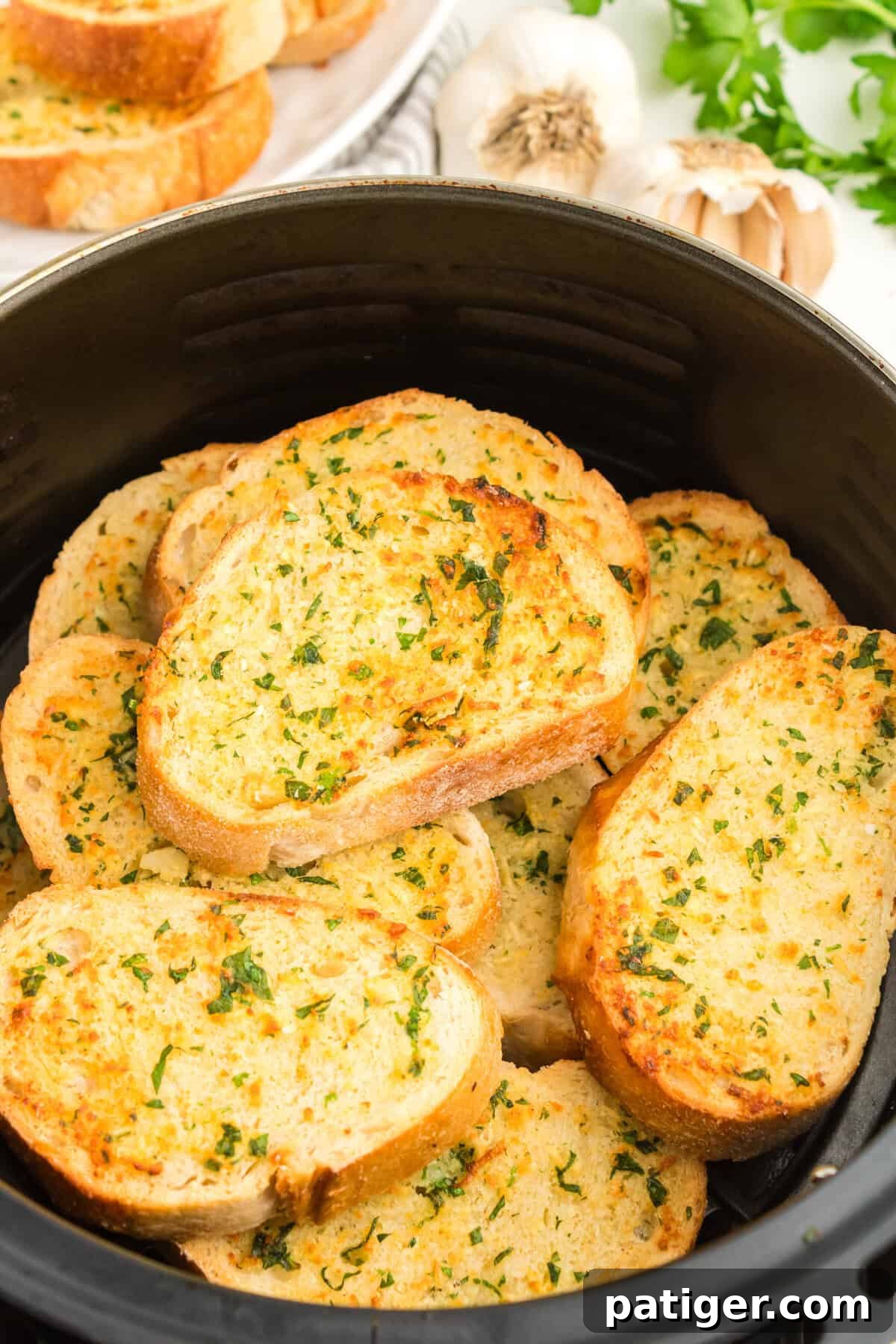 Golden Garlic Bread in Minutes 8 Stack of thick, crispy air fryer garlic bread slices in an air fryer basket, ready to be served.