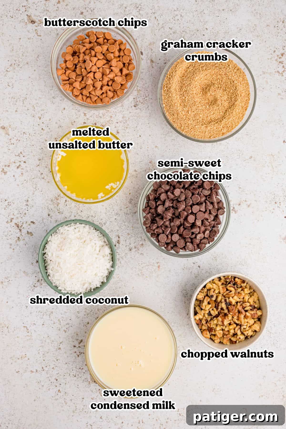 Butterscotch chips, chocolate chips, graham cracker crumbs, shredded coconut, chopped walnuts, sweetened condensed milk, and melted butter in bowls.