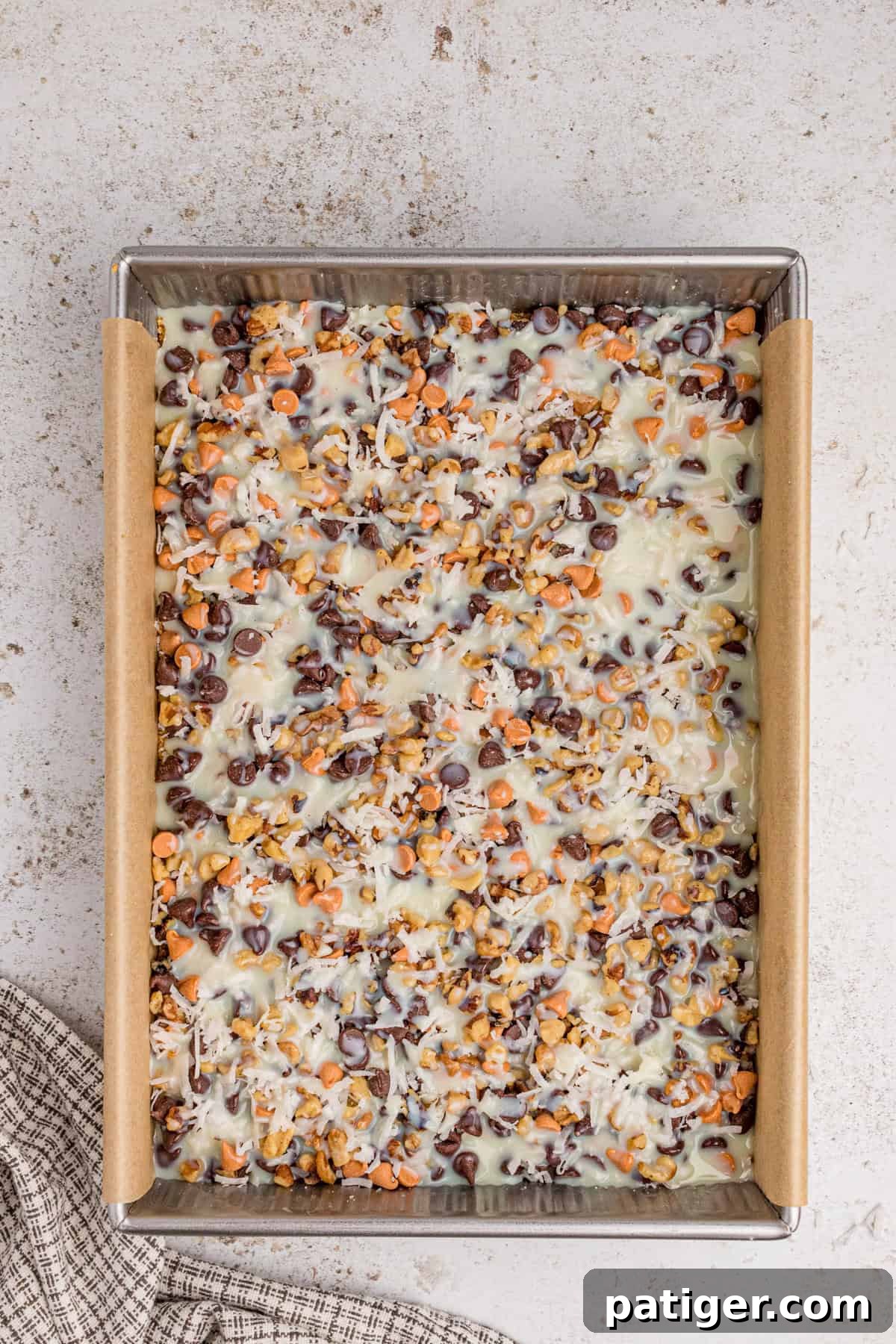 Sweetened condensed milk poured evenly over ingredients in pan.