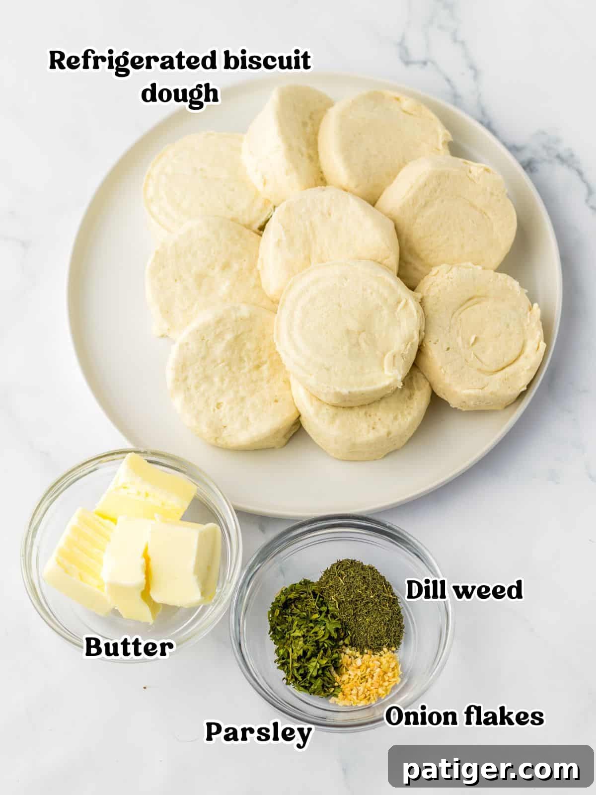 Aromatic Pull-Apart Herbed Biscuits 4 Ingredients for savory monkey bread: refrigerated biscuit dough, cubed salted butter, dried dill weed, dried onion flakes, and dried parsley, arranged neatly for preparation.
