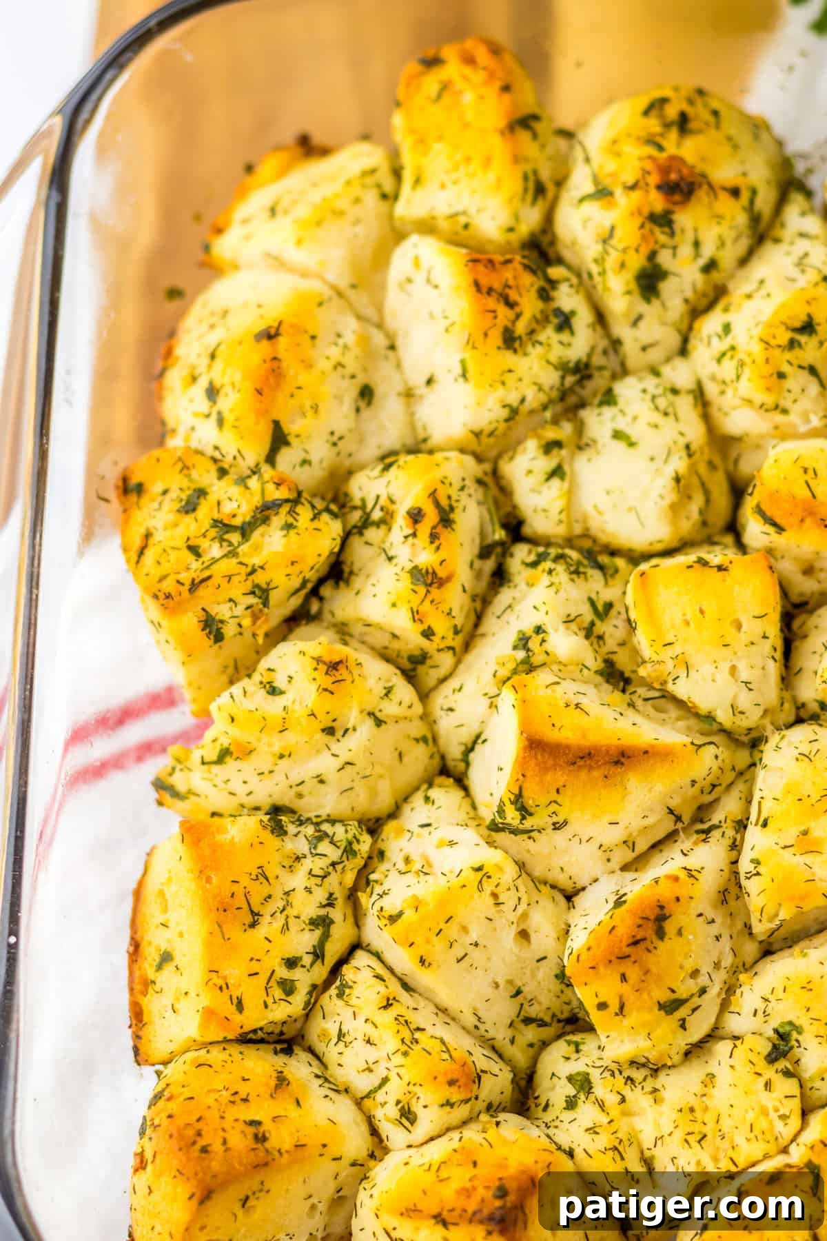 Aromatic Pull-Apart Herbed Biscuits 6 A close-up view of savory monkey bread, baked to a golden brown and still warm in a square glass dish, ready to be served.