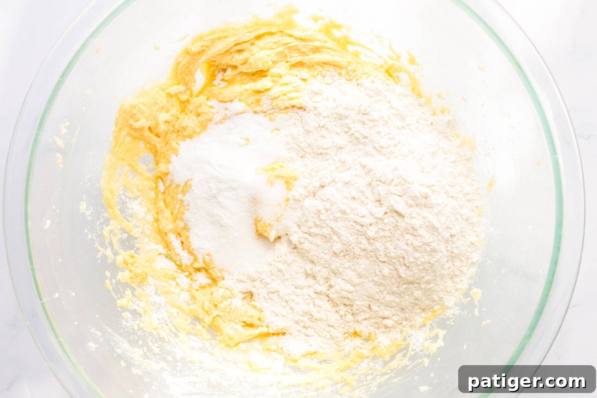 Ultimate Slow Cooker Chocolate Chip Cookie 6 A glass bowl showcasing the wet and dry ingredients partially mixed into a cookie dough, illustrating the careful process of combining them without overmixing.