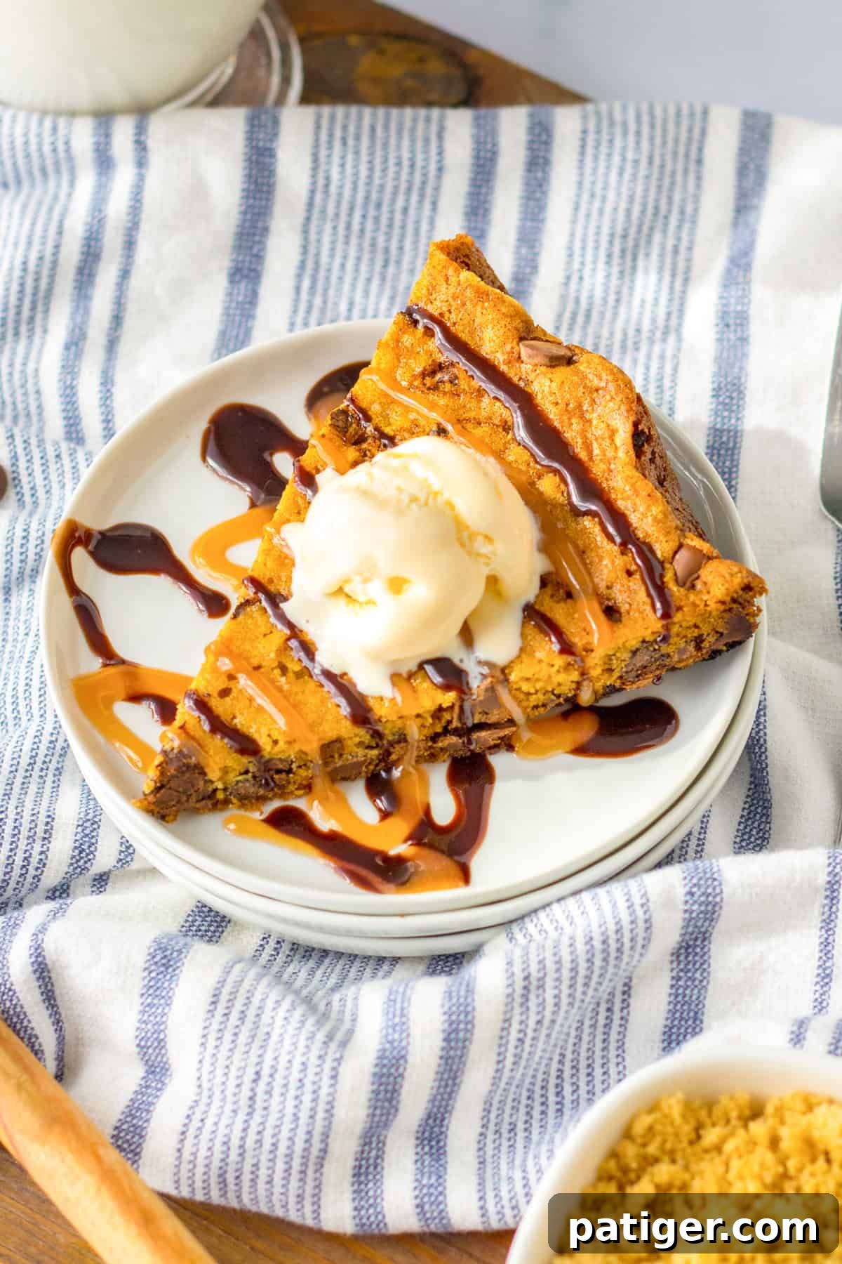 Ultimate Slow Cooker Chocolate Chip Cookie 9 A beautifully presented triangular slice of slow cooker chocolate chip cookie, topped with creamy vanilla ice cream and artfully drizzled with both chocolate and caramel syrup, ready to be enjoyed.