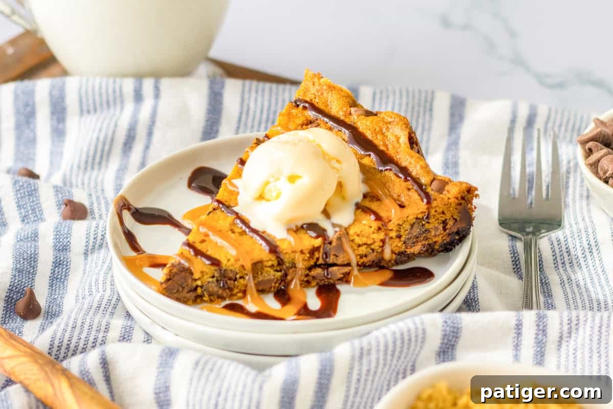 Ultimate Slow Cooker Chocolate Chip Cookie 10 A close-up shot of a thick, gooey slice of crockpot chocolate chip cookie cake, topped with a generous scoop of vanilla ice cream, and beautifully drizzled with both chocolate and caramel sauces, highlighting its rich texture.