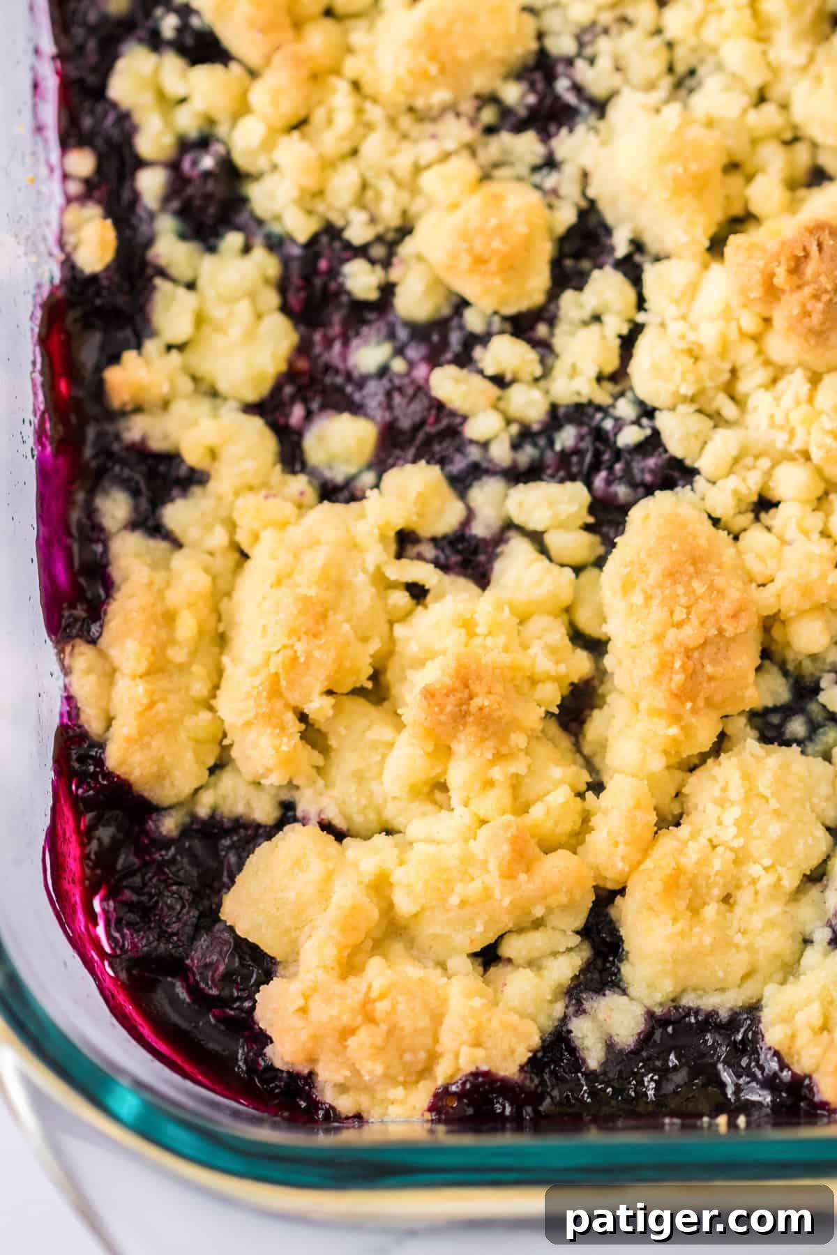 Blueberry cobbler made with cake mix in a clear glass baking dish, fresh from the oven.
