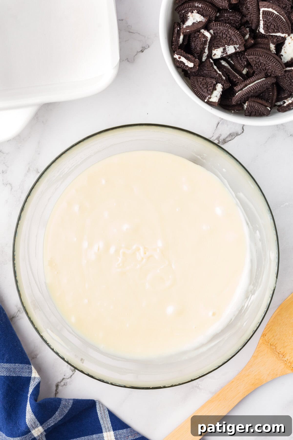Super Simple 3-Ingredient Oreo Fudge 5 Glass bowl of melted white chocolate and sweetened condensed milk.