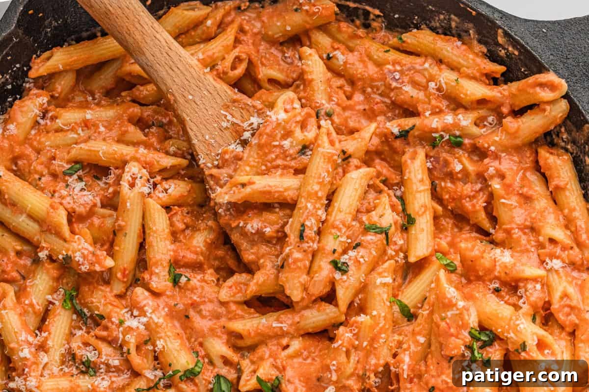 A large serving of creamy vodka sauce with penne pasta, garnished with fresh basil, ready to eat.