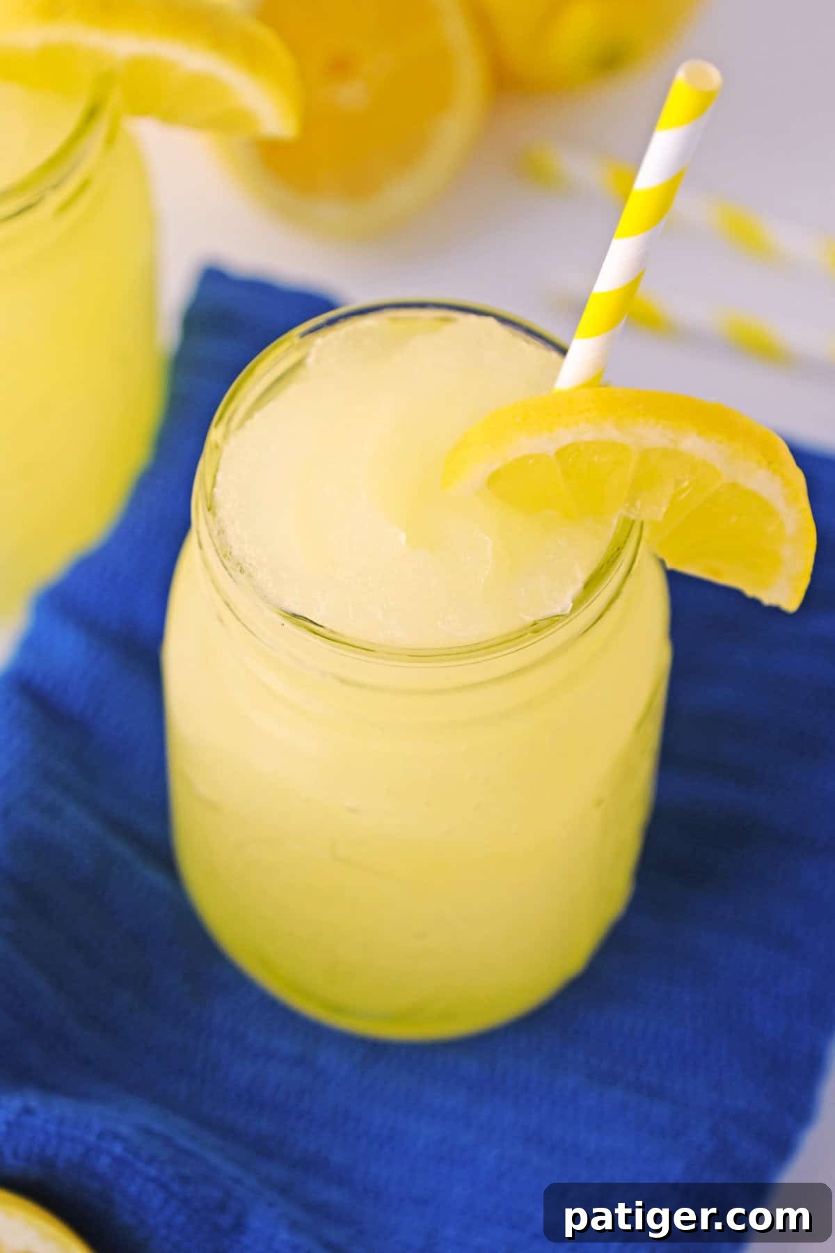Homemade lemonade slushy with straw and lemon wedge.