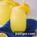 Frozen lemonade slushies garnished with slice of lemon and served in mason jars with yellow striped straws.