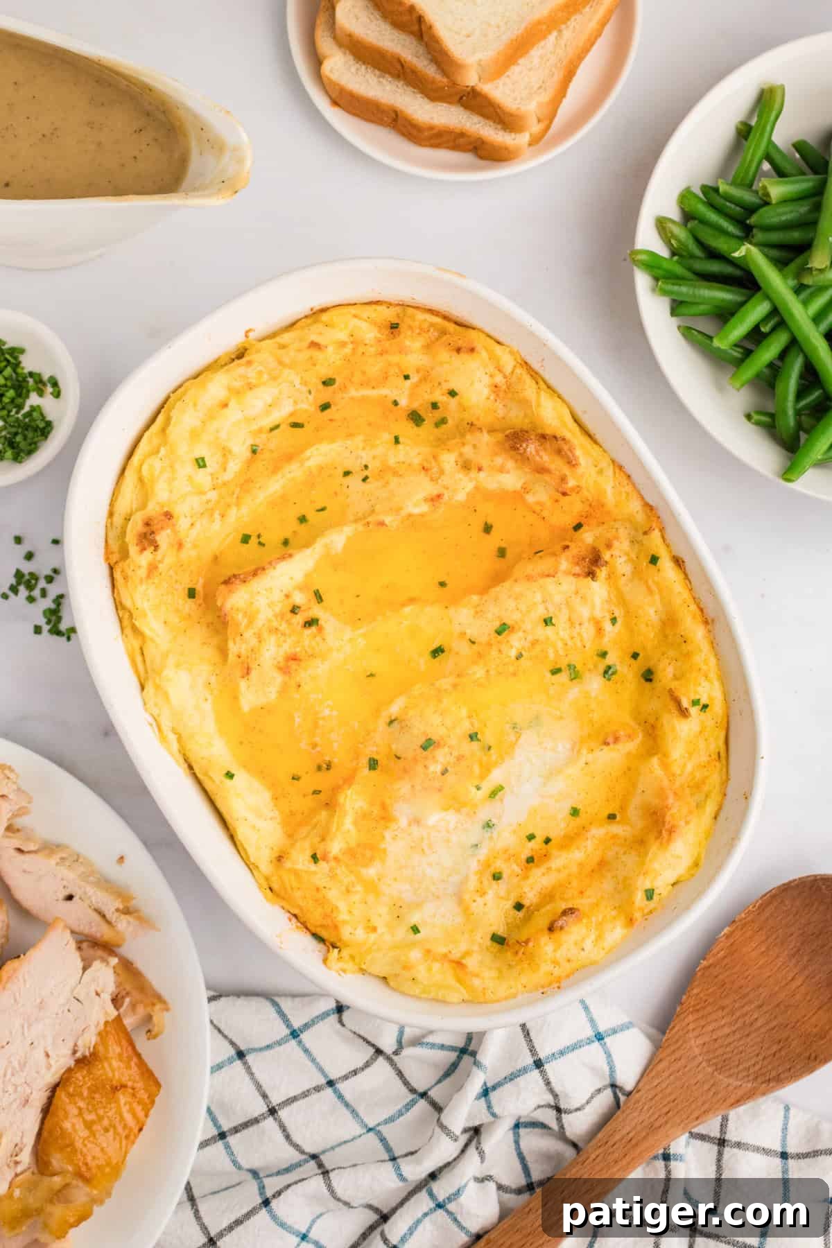 Spud-tacular Party Bites 2 Party potatoes in casserole dish surrounded by holiday meal including turkey, green beans, and gravy.
