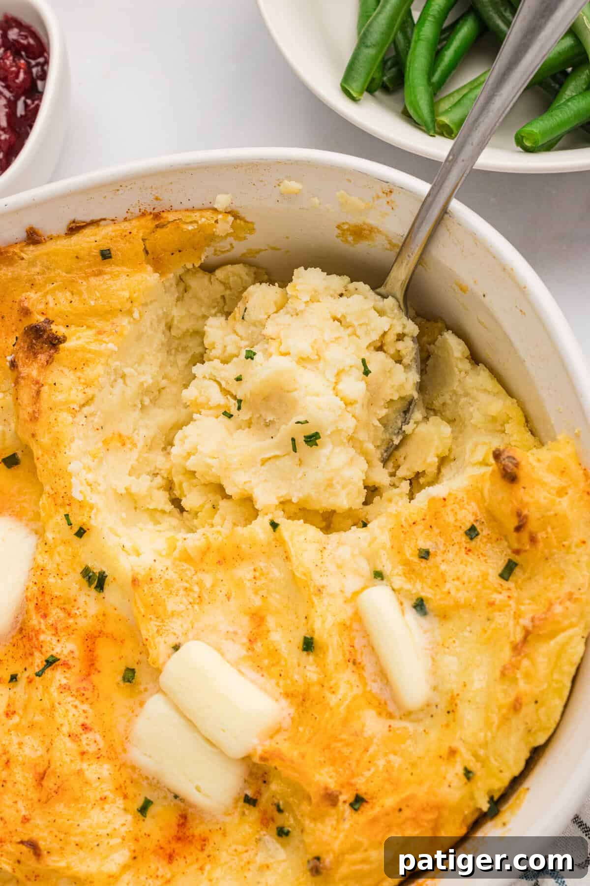Spud-tacular Party Bites 11 Serving spoon scooping party mashed potatoes out of baking dish.