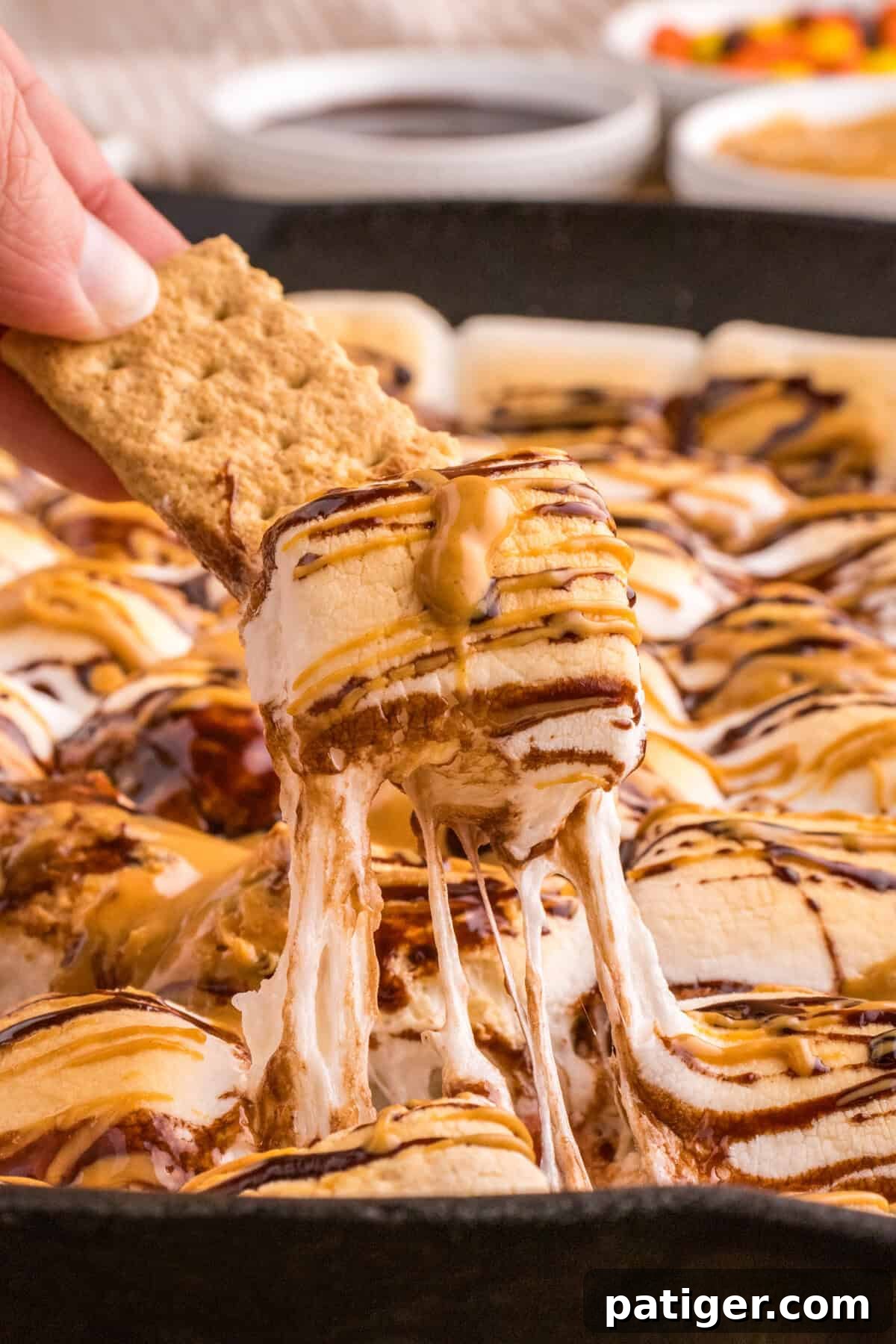 Graham cracker being dipped in chocolate peanut butter s'mores dip.