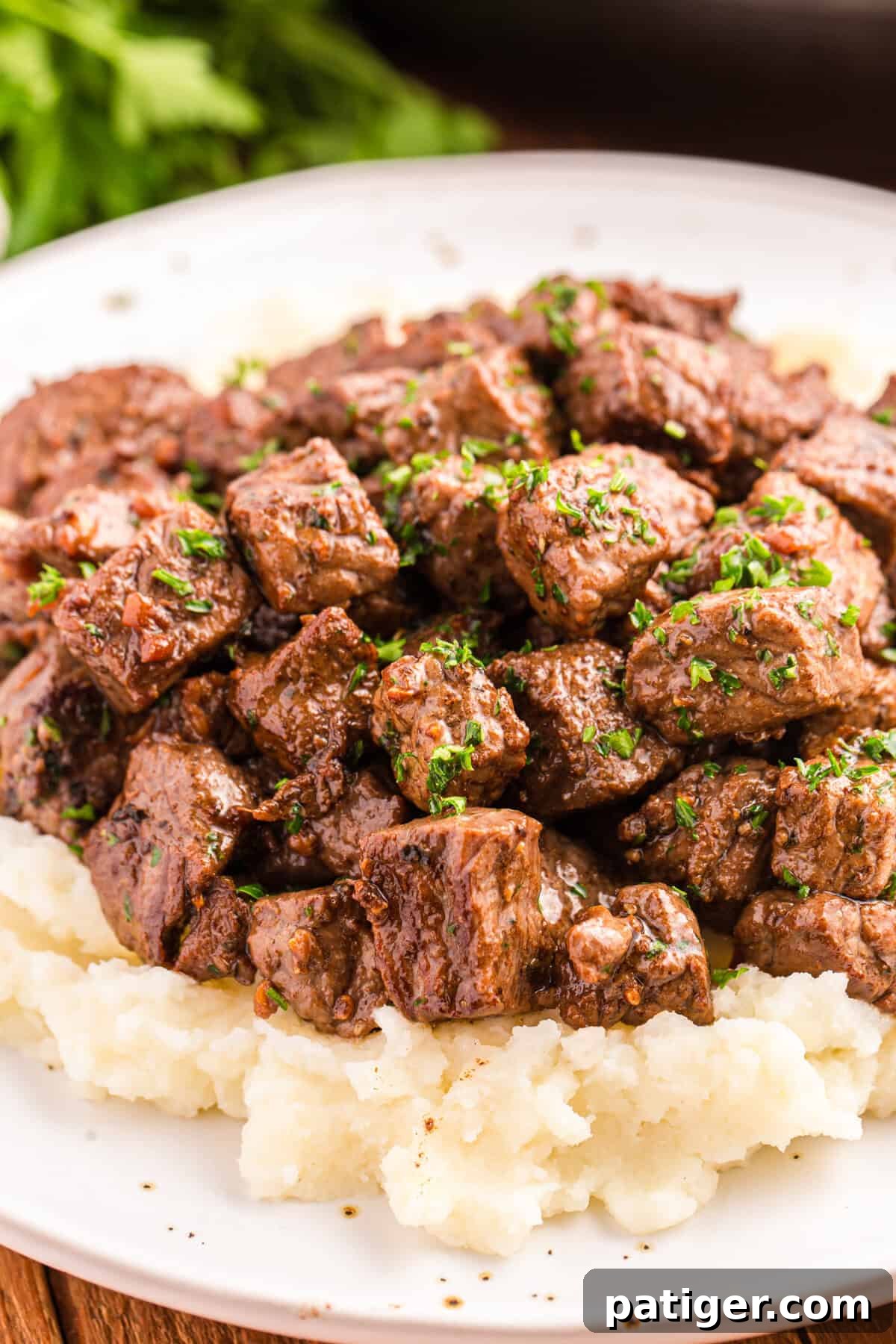 Golden Garlic Steak Bites 3 Steak bites with garlic butter served on bed of mashed potatoes.