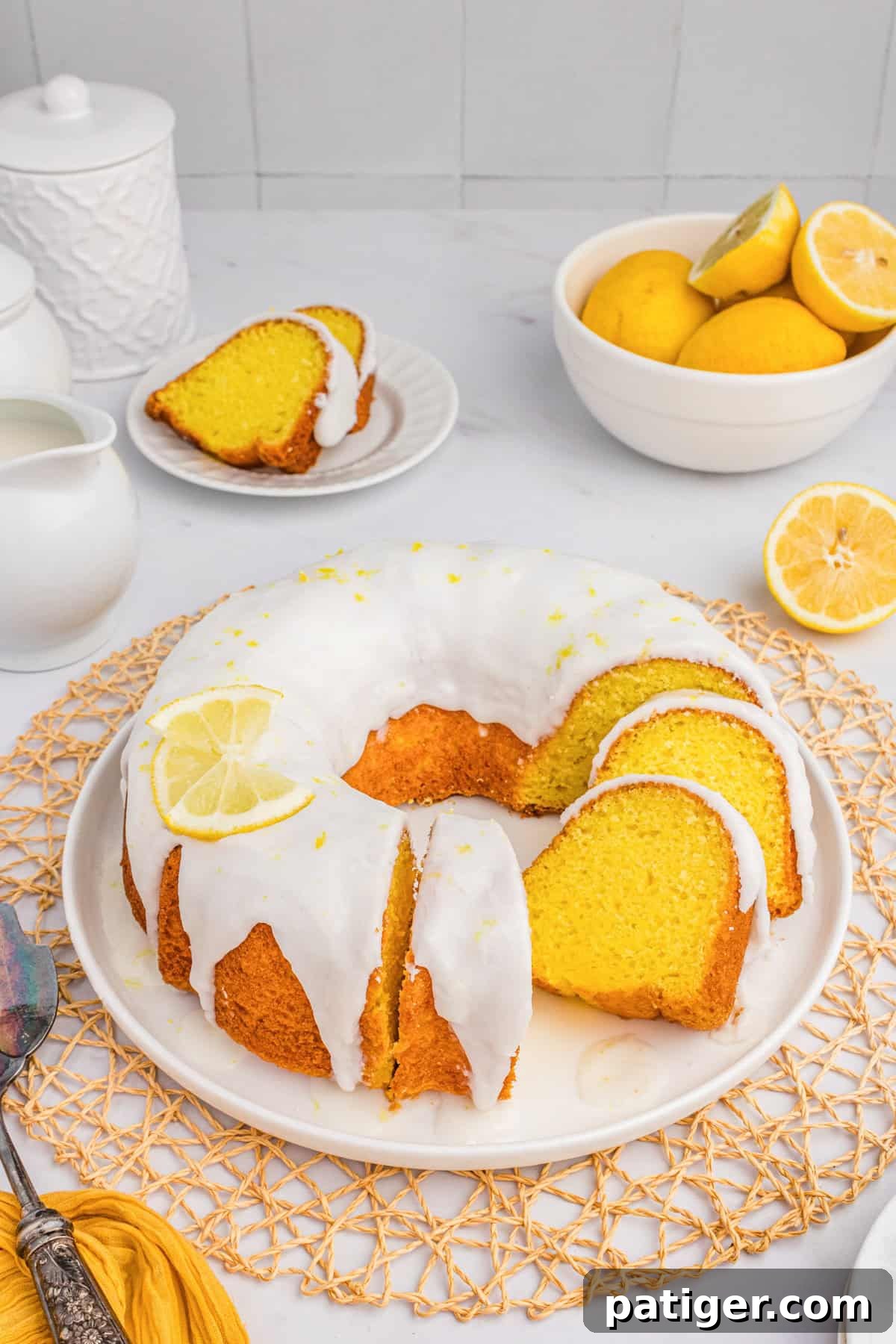 Lemon bundt cake with cake mix and a sweet lemon glaze. Sliced to show moist yellow cake. Fresh lemons in background.