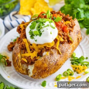 Taco stuffed baked potato with taco-seasoned ground beef, split open and generously topped with shredded cheese, sour cream, salsa, and green onions.